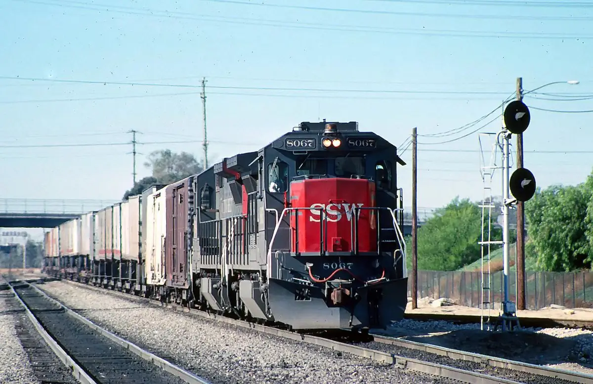A freight train passing through the railroad junction at Colton California with signals and tracks visible