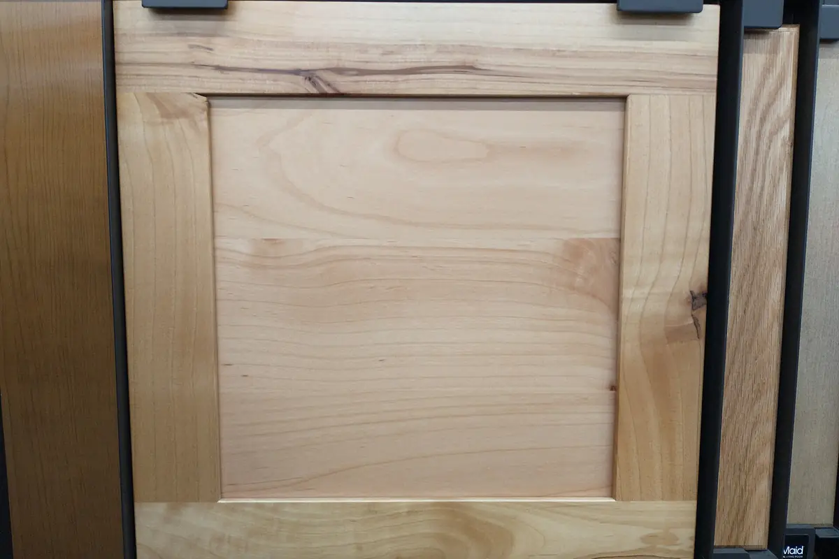 An unfinished maple shaker cabinet door sample on a display rack, showing the frame and flat centre panel