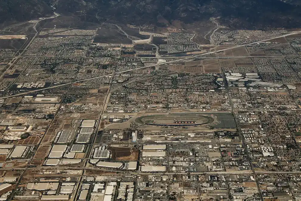 Aerial view over Fontana California showing the speedway oval, warehousing and tract housing spreading toward the hills