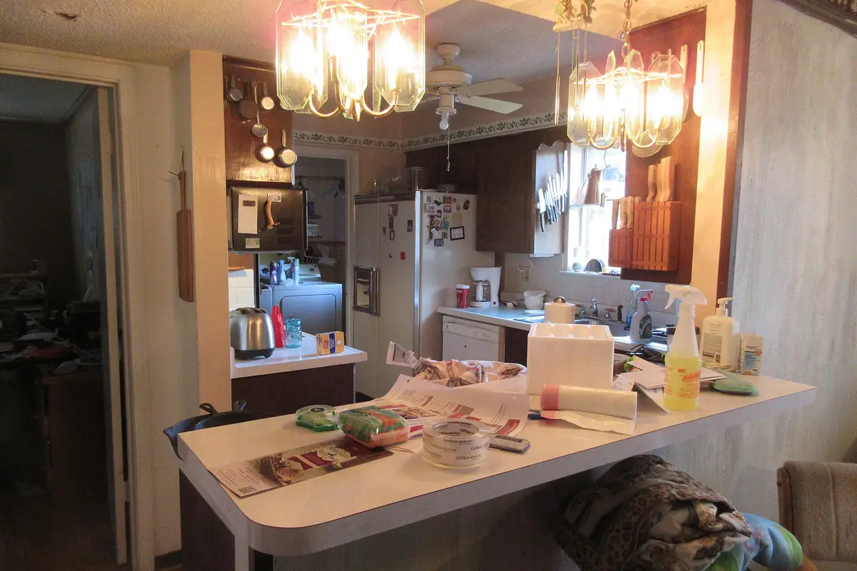 A dated kitchen with stained wood cabinet fronts, a laminate counter and a small window over the sink