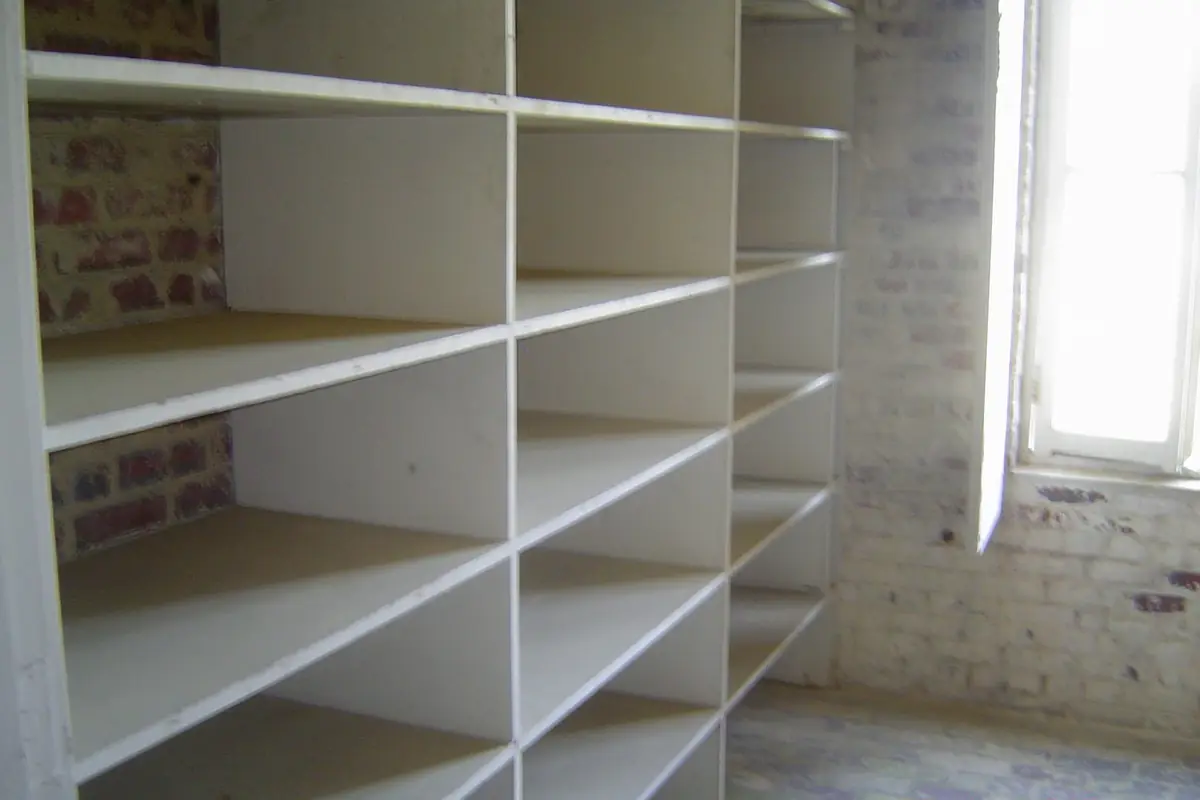 Deep pantry shelving stacked with jars and tins, fitted into a dedicated storage room
