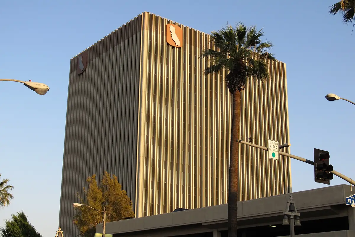 The California Tower in downtown Riverside California, a gold clad modernist office building beside a palm tree